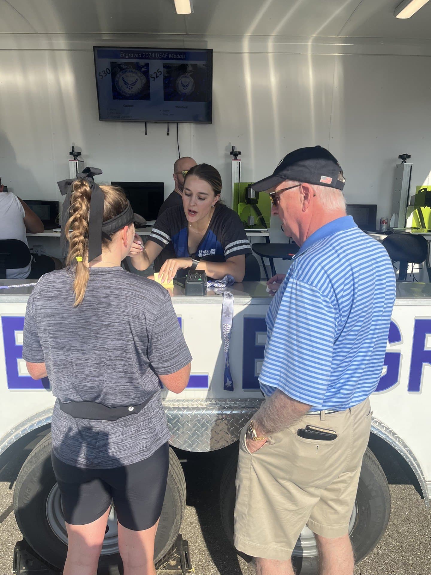 Runners at the Finish Line Engravers branded engraving booth at the Air Force Marathon, staff helping at the counter