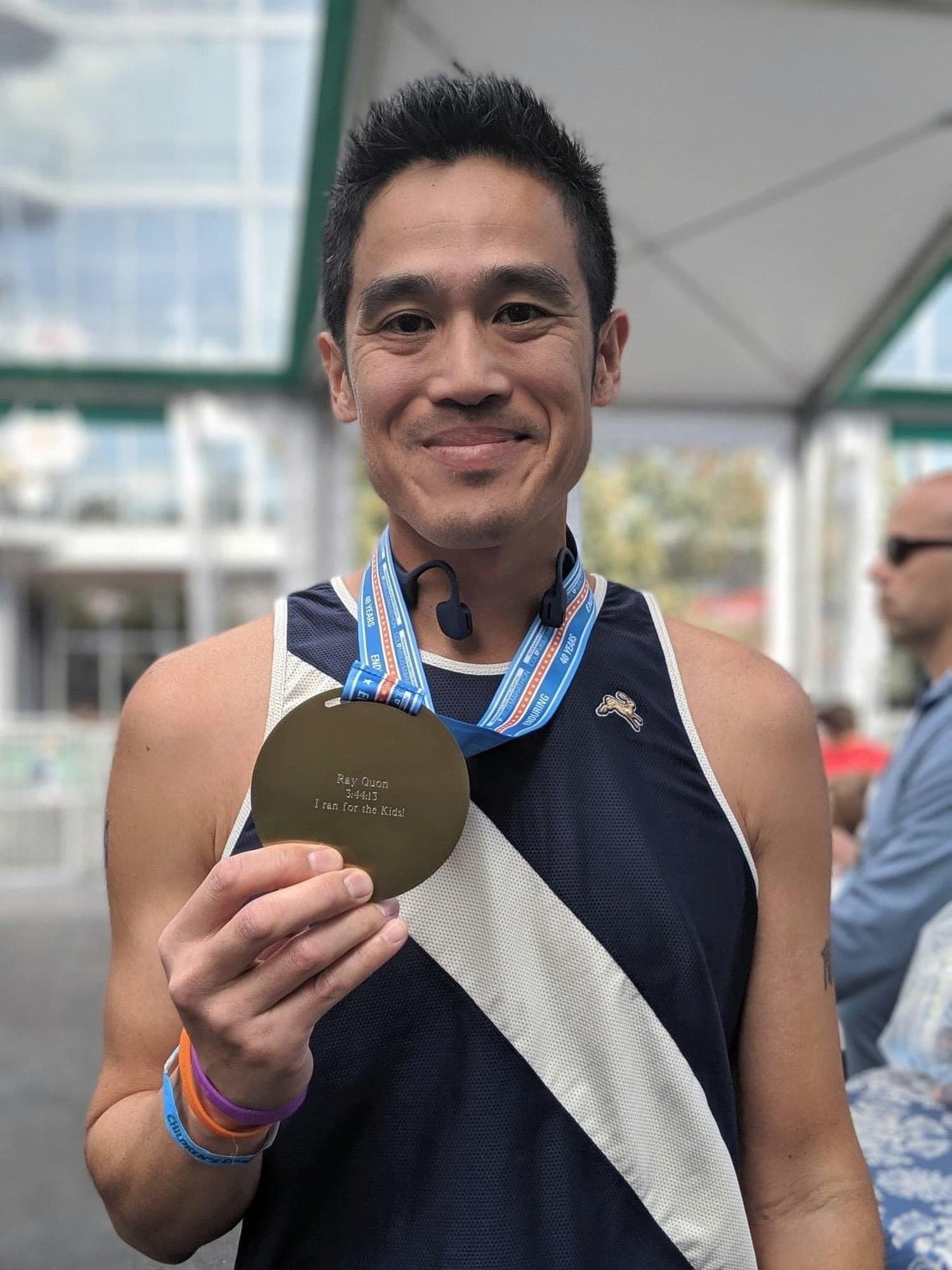 Runner holding his Columbus Marathon medal engraved with his name, finish time, and a personal message