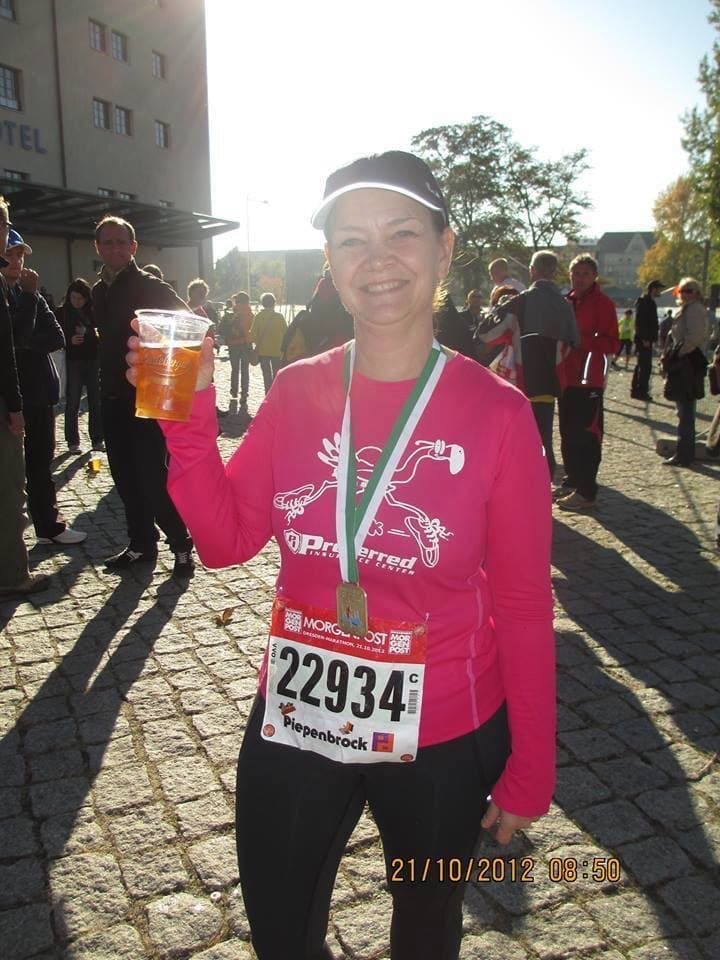 Kris Olsen at the Dresden Half Marathon in Germany, with the engraved finisher medal that inspired Finish Line Engravers