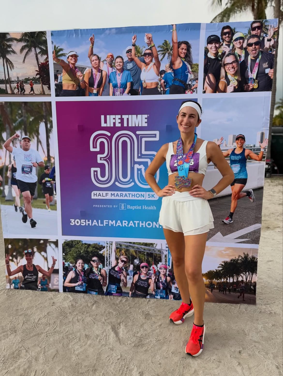Finisher posing with her medals at the branded Miami 305 finish festival backdrop