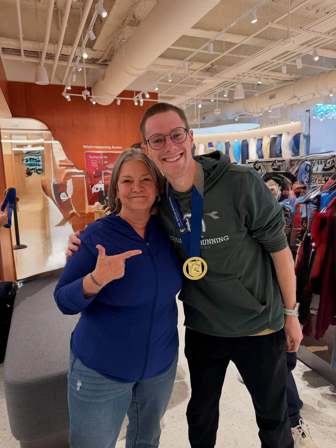 Boston Marathon finisher wearing his medal, celebrating at the Finish Line Engravers station