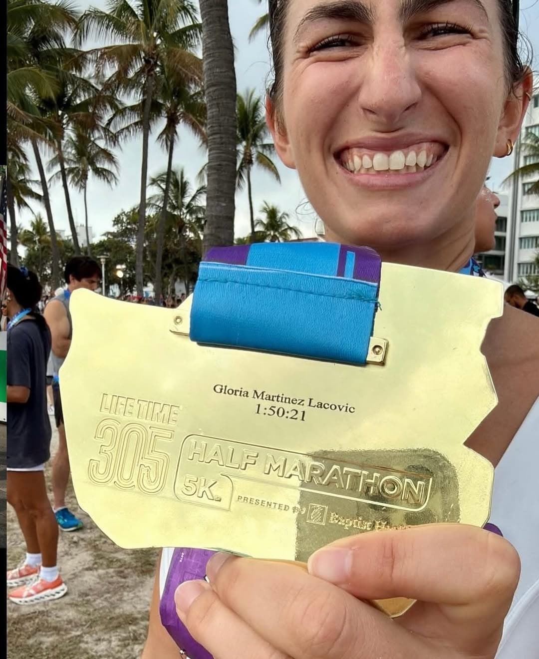 Runner beaming as she shows her medal engraved with her name and finish time at the Miami 305 Half Marathon