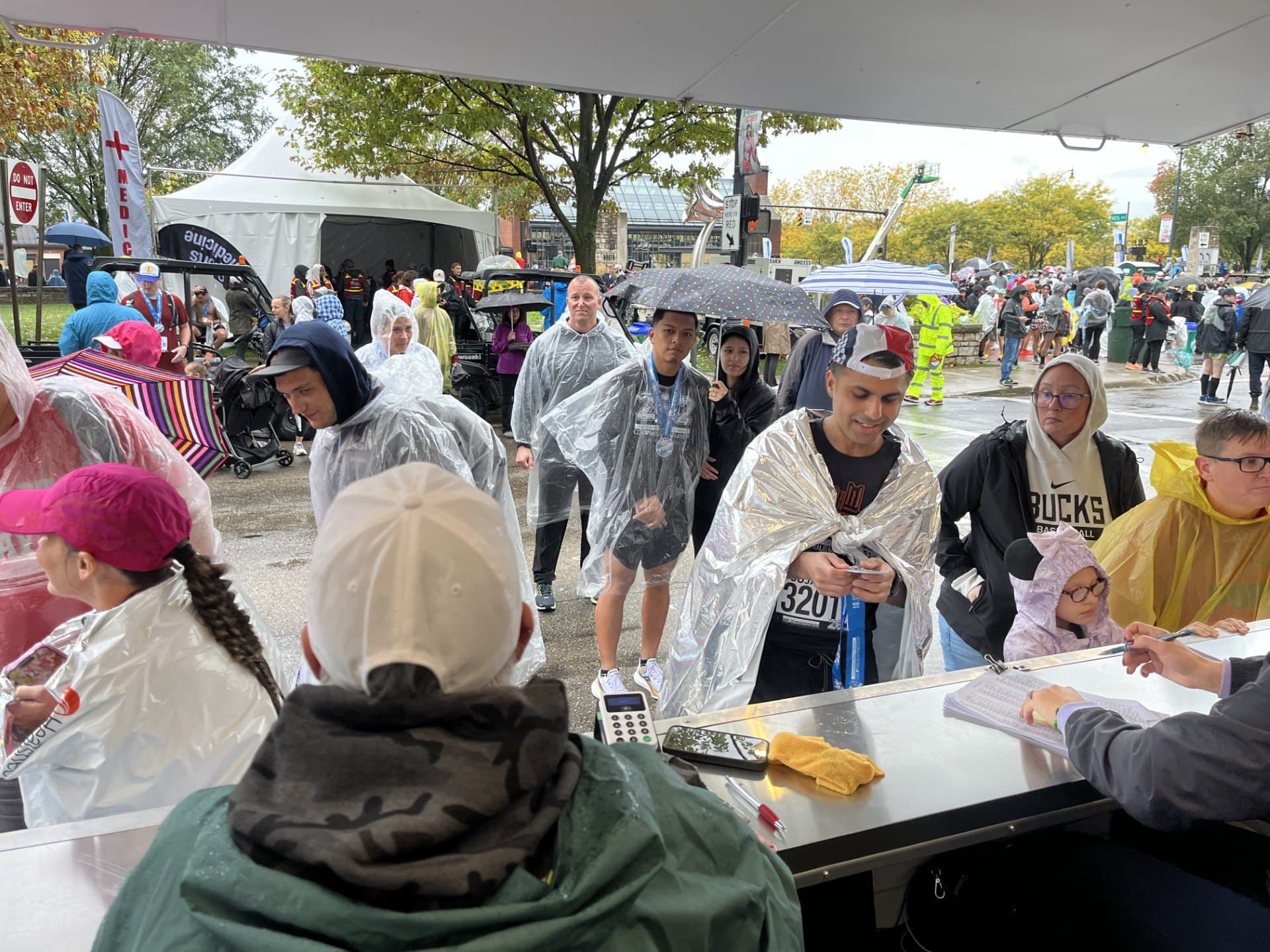 The Finish Line Engravers line running steadily in the rain — runners in ponchos waiting at the engraving counter