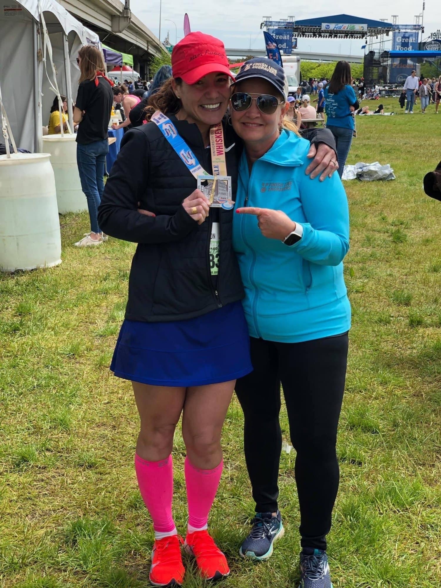 Finish Line Engravers team member celebrating with a runner and her engraved medal at the Kentucky Derby Festival